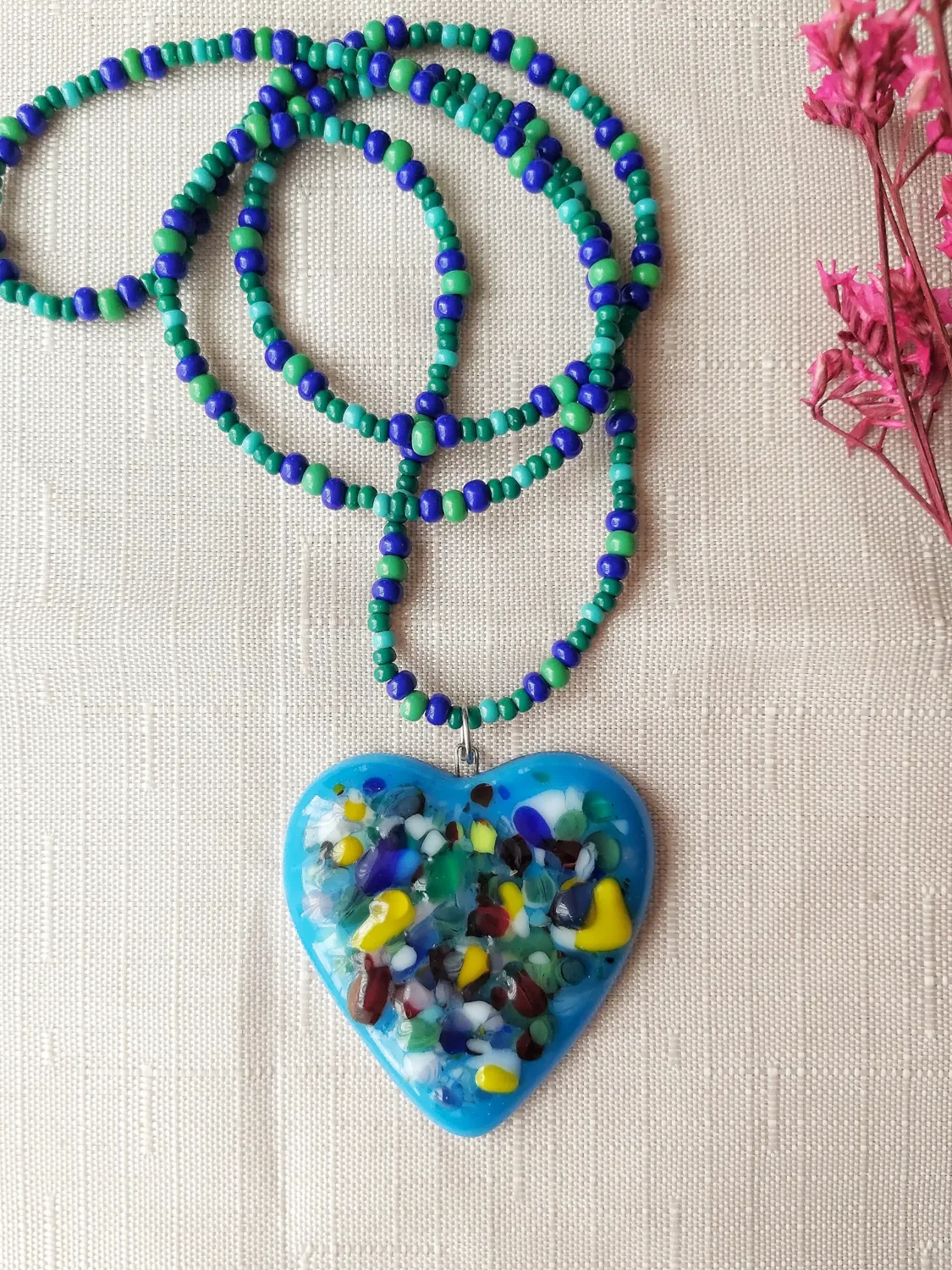 Collar de cuentas azules y verdes con un corazón de vidrio multicolor