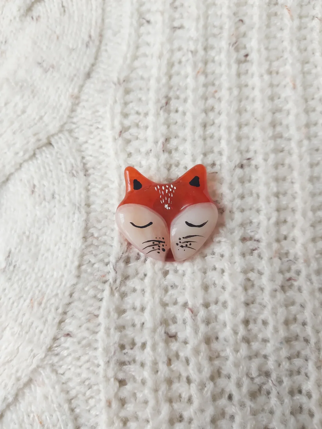 Pin con forma de gato de vidrio sobre una prenda tejida