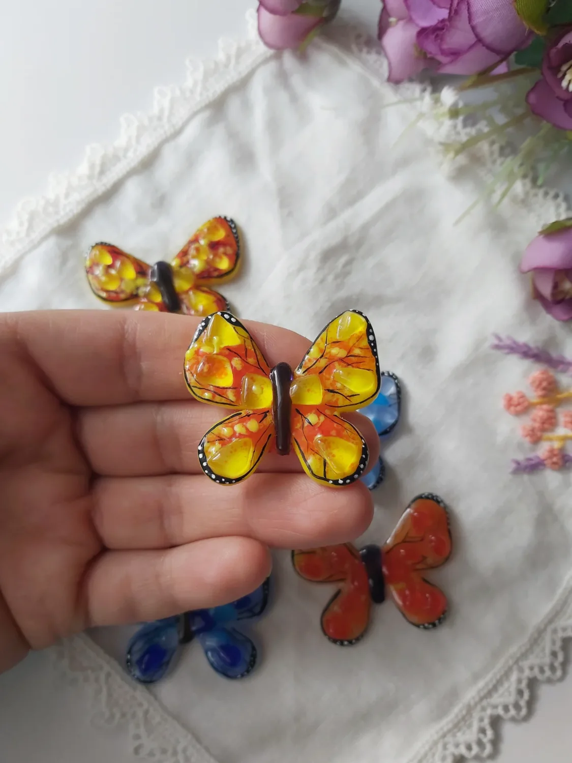 Mariposa de vidrio amarillo y naranja sostenida en una mano